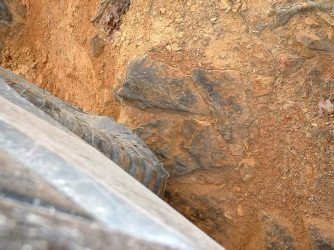 1987 Ford F-150 - A tire is partially visible against a steep dirt embankment with scattered rocks.