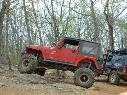 1987 Ford F-150 - Two Jeeps navigate a rocky trail in a wooded area.