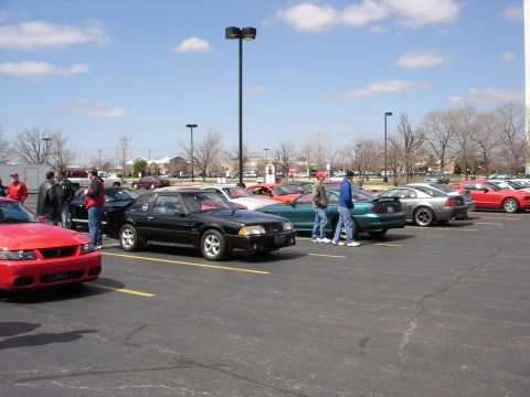 1998 Ford Taurus - A black coupe with a spoiler is parked in a lot with other vehicles.