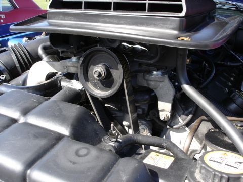 1998 Ford Taurus - The engine bay features a prominent belt and pulley system, with a large black air intake component.