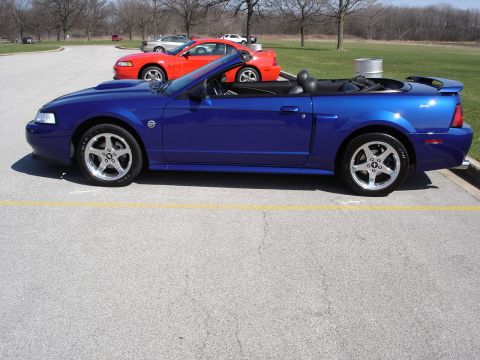 1998 Ford Taurus - A blue convertible is parked in a lot with other vehicles visible in the background.
