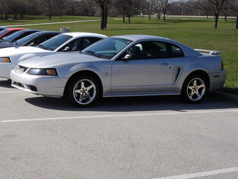 1998 Ford Taurus - Several cars are parked in a lot, with a silver coupe in the foreground.