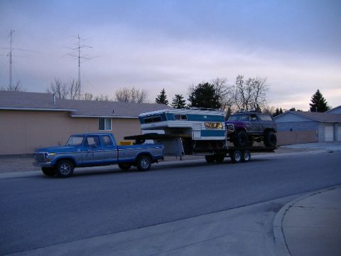 1979 Ford Bronco - Ford pickup tows a camper and a lifted SUV on a trailer.