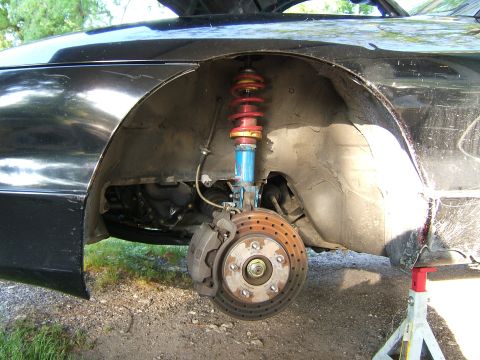 1996 Ford Probe - Close-up view of the front wheel well and suspension of a black car, showing the brake system and coilover.