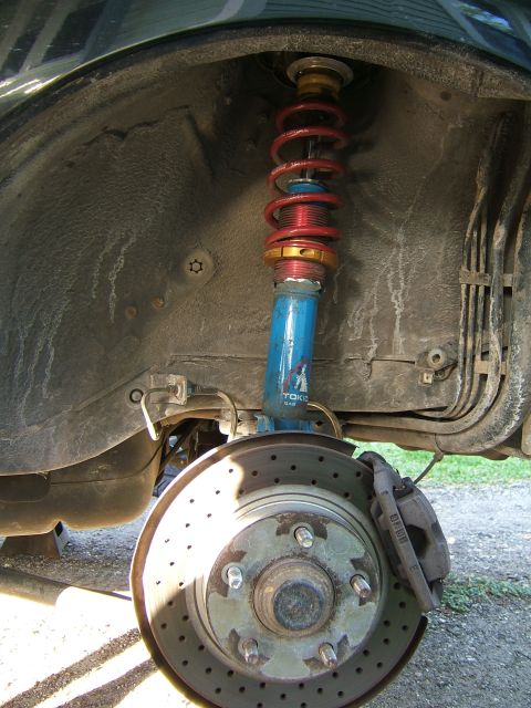 1996 Ford Probe - Close-up of a car's front wheel suspension, a blue Tokico shock absorber and a red coilover spring.