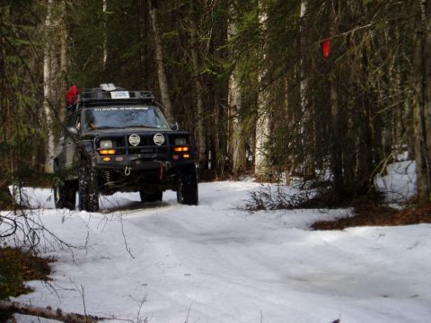 2000 Ford E350 - Off-road vehicle navigates a snow-covered trail in a dense forest.
