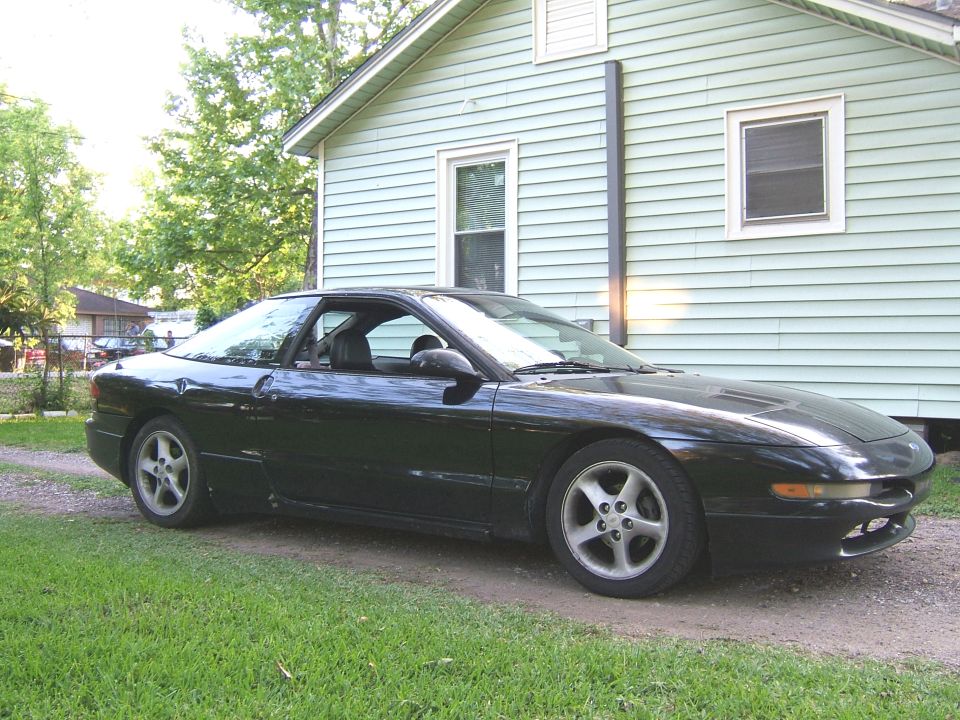 Black 1996 Ford Probe parked next to a light blue house