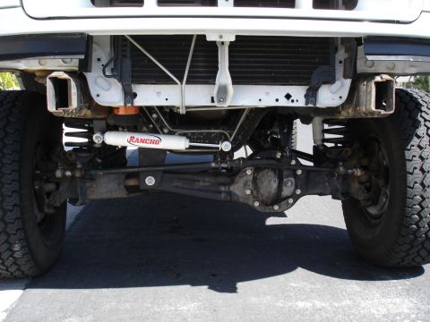 1996 Ford Bronco - Undercarriage view of a white truck's front axle and suspension components.