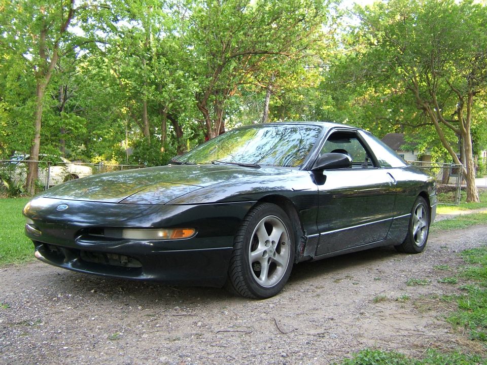 Black Ford Probe coupe parked on gravel drive, three-quarter front view with silver alloy wheels