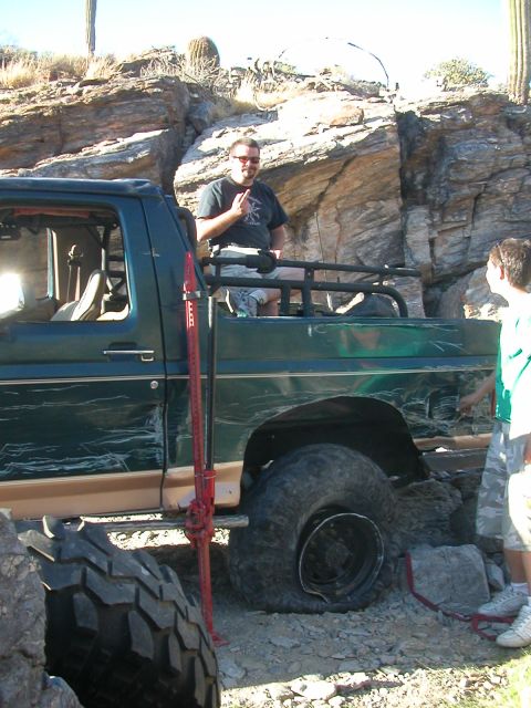 1984 Ford Bronco - A group of people are gathered around a modified off-road truck stuck in a rocky terrain.