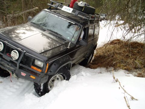 2000 Ford E350 - A black Jeep Cherokee navigates a snowy trail, its front end partially submerged in snow.