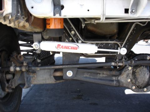 1996 Ford Bronco - Underneath view of a 1996 Ford Bronco, highlighting the Rancho steering stabilizer and front axle components.