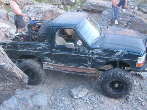 1984 Ford Bronco - This modified SUV navigates a challenging rocky terrain, its off-road capabilities.