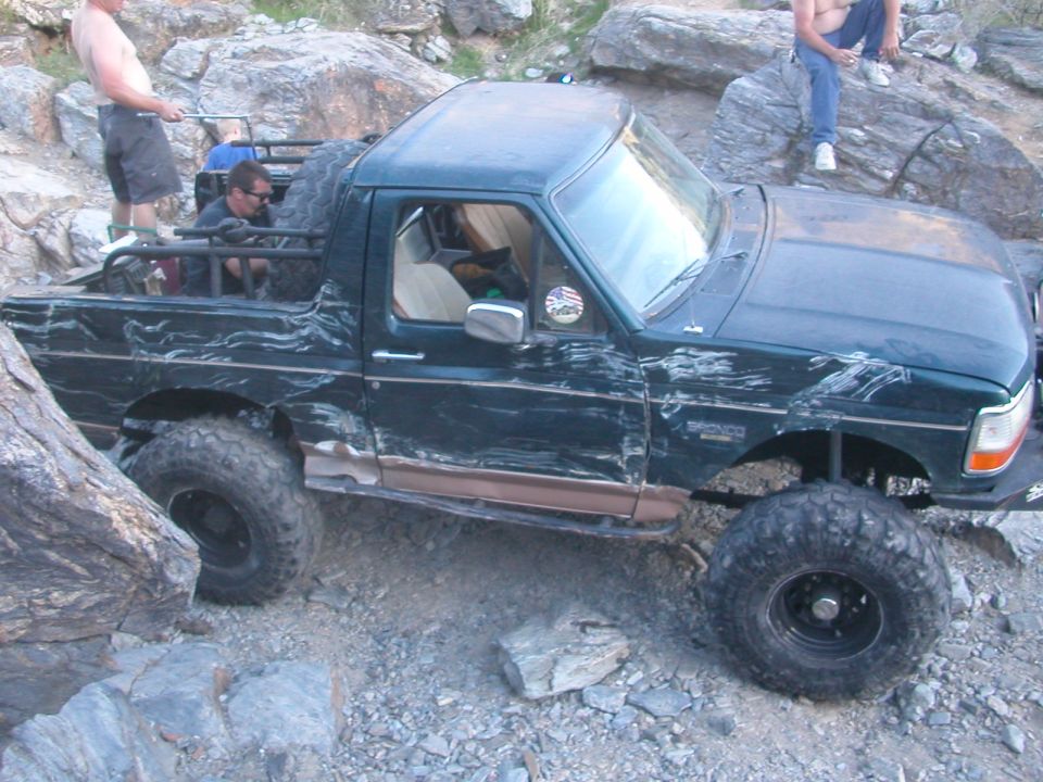 Dark green off-road SUV with large tires on a rocky trail