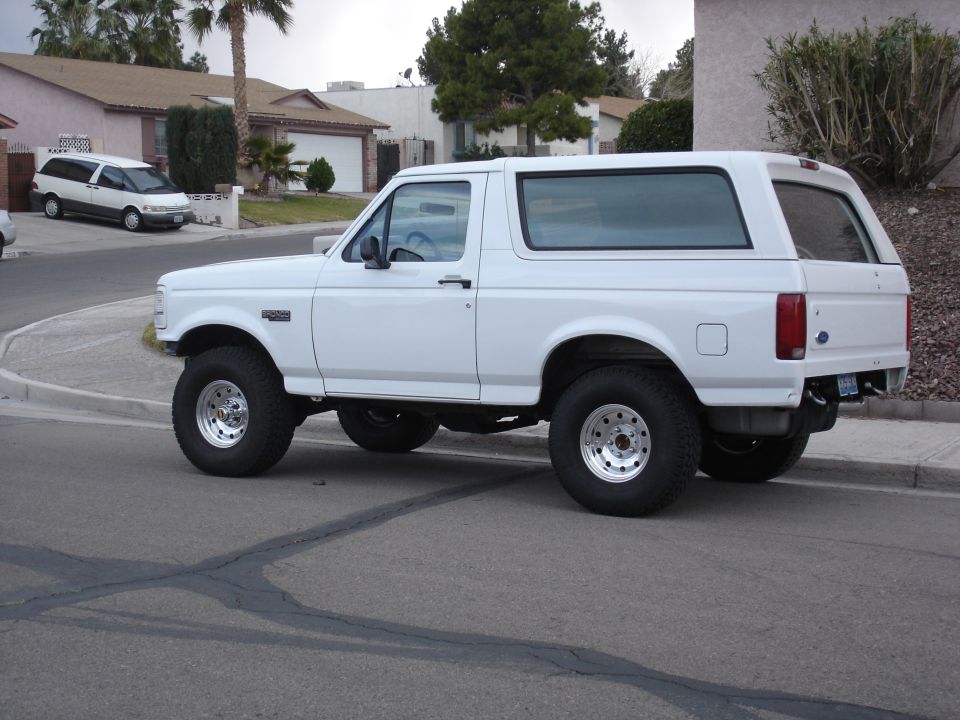 White Ford Bronco, lifted, with aftermarket wheels, seen from the side