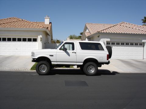 1996 Ford Bronco - White 1996 Ford Bronco parked on a street in front of a house with a two-car garage.