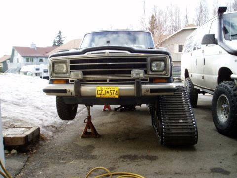 2000 Ford E350 - Jeep Cherokee fitted with tracks, parked next to a white van.