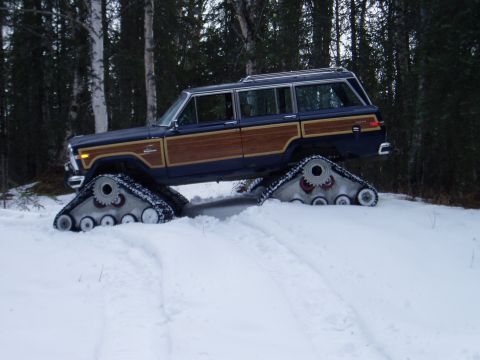 2000 Ford E350 - Wood-paneled Jeep Grand Wagoneer equipped with snow tracks navigates a snowy forest.