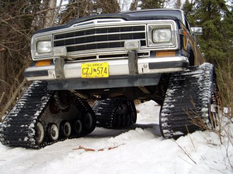 2000 Ford E350 - This modified Jeep Cherokee features a track system for off-road snow travel, with an Alaska license plate visible.