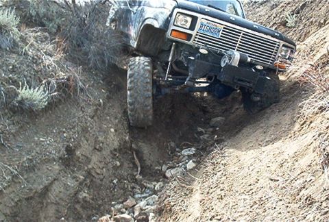 1986 Ford Bronco - This off-road vehicle, likely from the early 1980s, is shown tackling a challenging dirt path.