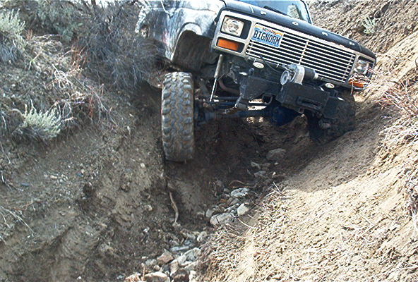 Black off-road vehicle with 'BIGNORM' license plate navigating a steep dirt ditch