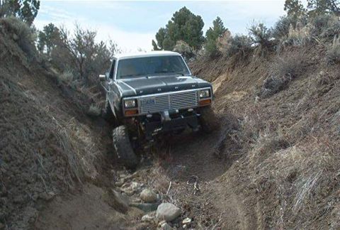 1986 Ford Bronco - Ford Bronco navigates a challenging off-road trail with steep inclines and loose rocks.