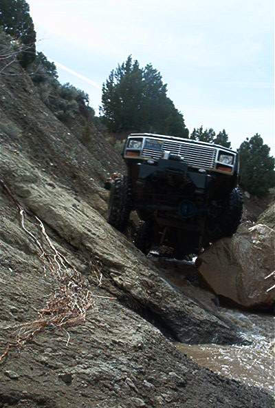1986 Ford Bronco - A black Jeep Cherokee XJ navigates a challenging rocky terrain, demonstrating its off-road capabilities.