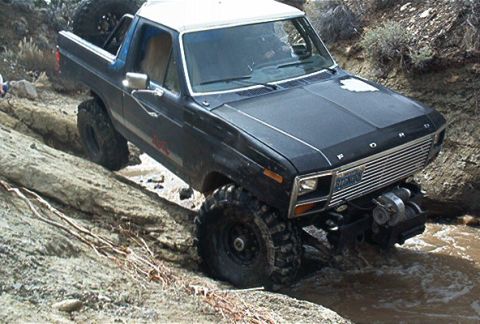 1986 Ford Bronco - This 1986 Ford Bronco is tackling a challenging off-road course with steep inclines and water obstacles.