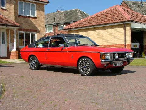 1976 Ford Granada - This 1976 Ford Granada coupe features a distinctive red exterior with a black vinyl roof and is parked on a brick driveway.