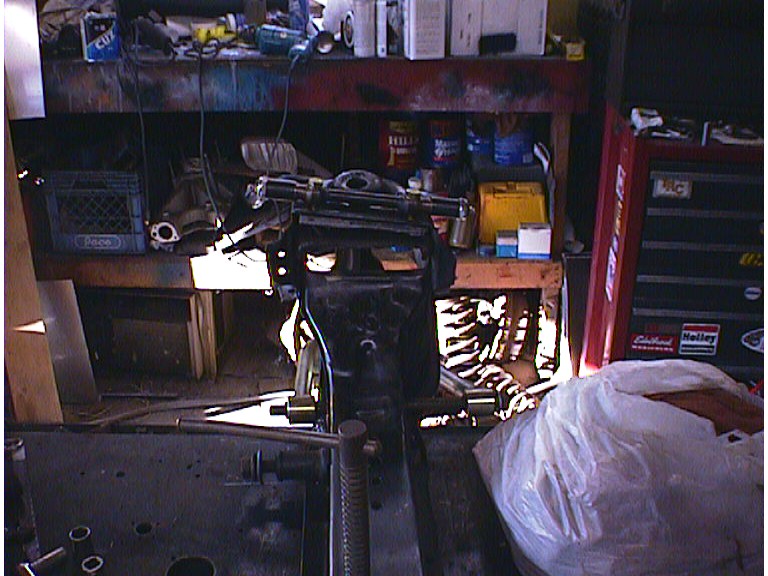 Dark garage workbench with auto parts, red toolbox, and cluttered shelving
