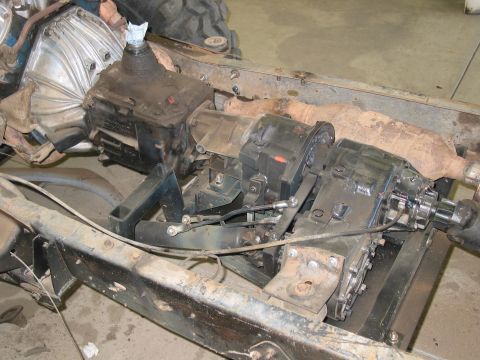 1981 Ford Bronco - Close-up view of the transfer case and transmission assembly mounted on a vehicle frame.