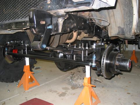 1981 Ford Bronco - Vehicle's front axle and suspension components are elevated on jack stands for maintenance.