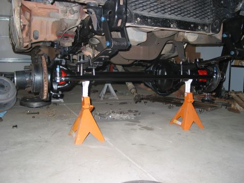 1981 Ford Bronco - Undercarriage of a 1981 Ford Bronco, showing the front axle and suspension components supported by jack stands.