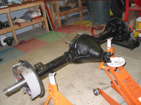 1981 Ford Bronco - A black rear axle assembly is supported by orange jack stands in a garage setting.