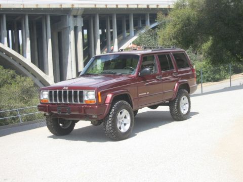 2000 Jeep Cherokee - This lifted Jeep Cherokee XJ is shown from a 3/4 front angle with a bridge in the background.