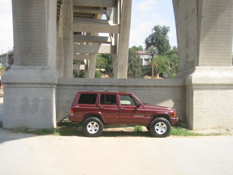 2000 Jeep Cherokee - Side view of a maroon 2000 Jeep Cherokee parked under a large concrete overpass.