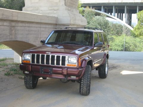2000 Jeep Cherokee - Maroon 2000 Jeep Cherokee lifted with off-road tires, parked under a bridge.