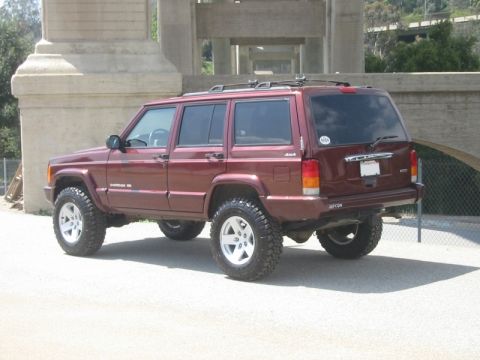 2000 Jeep Cherokee - This lifted Jeep Cherokee is parked outdoors with a bridge-like structure in the background.