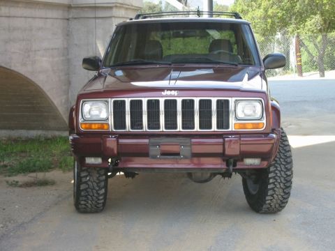 2000 Jeep Cherokee - Front view of a lifted maroon 2000 Jeep Cherokee with off-road tires parked outdoors.