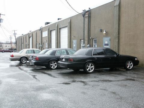 2001 Mercury Grand Marquis - Several police interceptor sedans are lined up outside a commercial building on a wet day.
