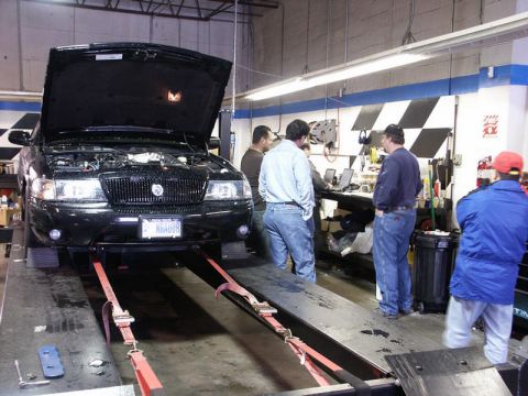 2001 Mercury Grand Marquis - A black 2001 Mercury Grand Marquis is positioned on a dynamometer in a workshop, with its hood up and several onlookers.