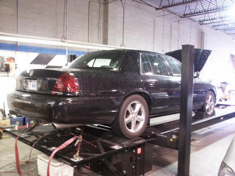 2001 Mercury Grand Marquis - A black sedan, identified as a Marauder, is positioned on a car lift with its hood open inside a workshop.