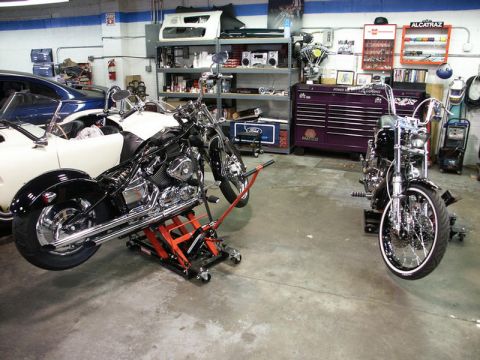 2001 Mercury Grand Marquis - A garage scene with two motorcycles, one being worked on with a lift, and various tools and car parts visible.