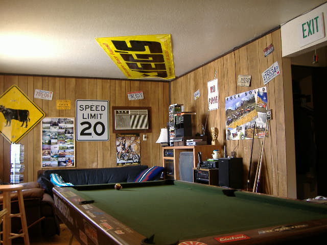 Room interior with pool table, speed limit sign, and license plates on wood-paneled walls