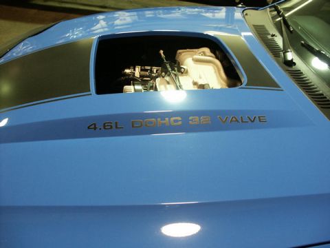 2001 Mercury Grand Marquis - A blue car features a cutout on the hood revealing its 4.6L DOHC 32 valve engine.