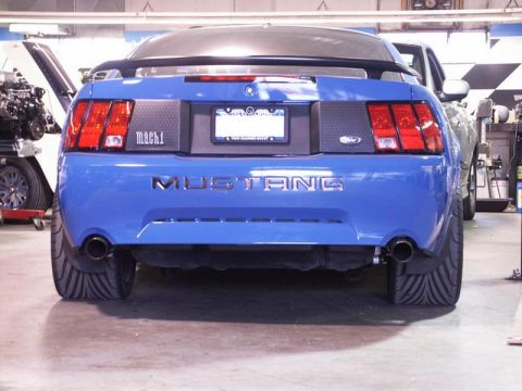 2001 Mercury Grand Marquis - Blue Ford Mustang Mach 1 with custom wide tires in a workshop setting.
