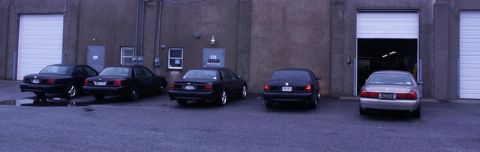 2001 Mercury Grand Marquis - Several sedans are parked outside a commercial building with multiple garage doors.