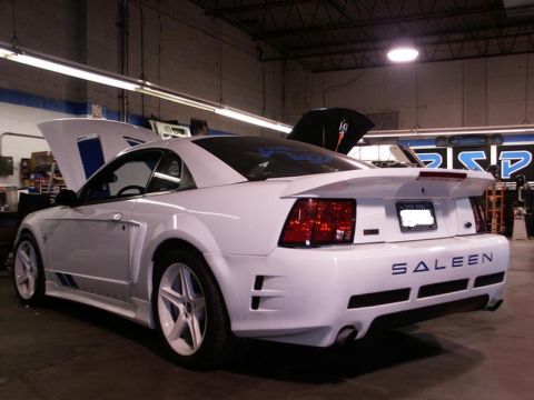 2001 Mercury Grand Marquis - White Saleen Mustang in a workshop, showing off its rear end and open hood.