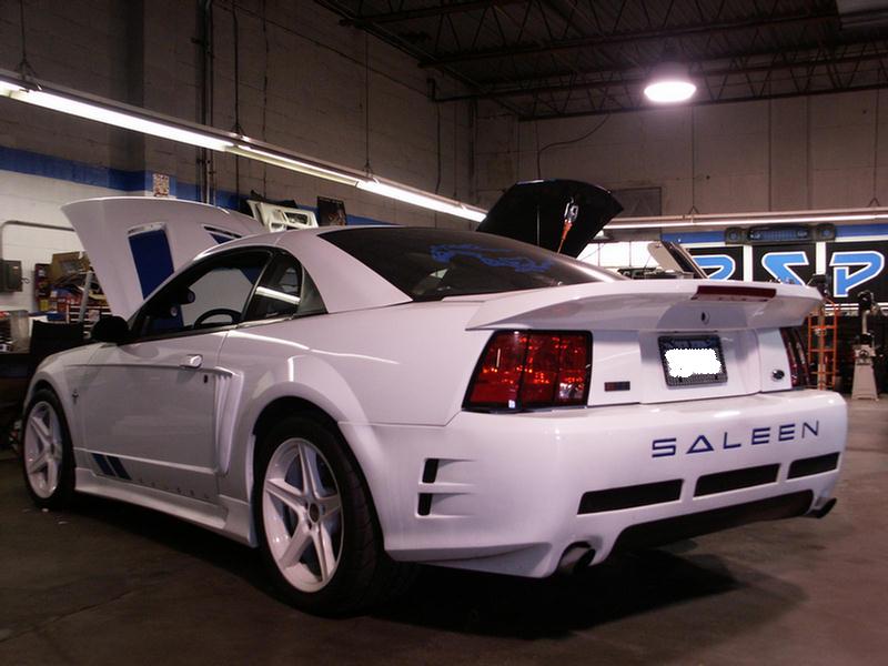 White Saleen Mustang with hood and trunk open, parked in a workshop. SALEEN text visible on rear bumper