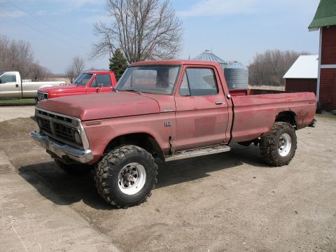1973 Ford F-250 - This red Ford F-250 pickup truck is parked on a dirt lot with farm buildings in the background.